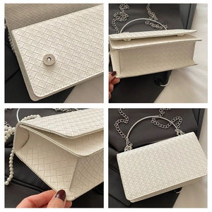 Detail view of white woven leather handbag with silver metal handle and pearl charms
