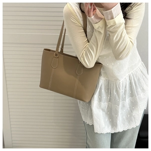 Detail of khaki tote bag with contrast white stitching and slender shoulder strap