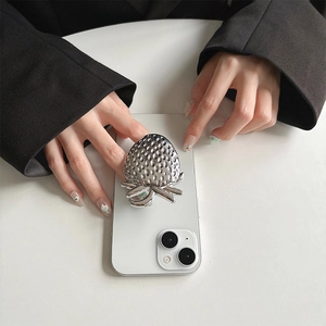 Detailed view of a silver 3D strawberry phone socket on a white smartphone