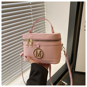 Detail of pink leather box bag with gold M logo, dual zippers, and top handle close-up