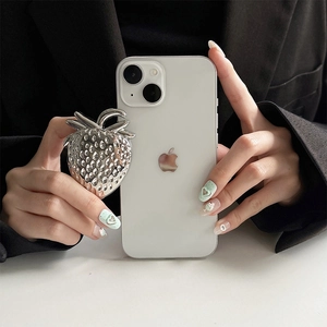 Detail of silver strawberry-shaped metal phone socket grip on white mobile back