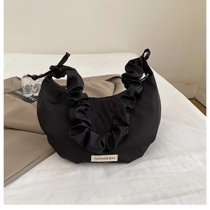 Close-up of black nylon dumpling bag with pleated handle and fashion label detail