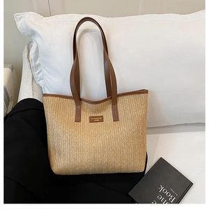Detail of straw tote bag featuring a leather strap and New York fashion patch