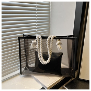 Detail of transparent PVC tote bag with white cotton rope handles and black leather trim