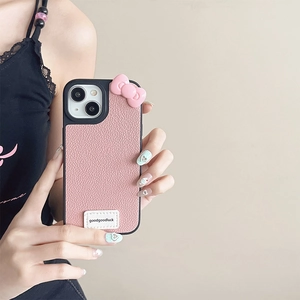 Pink lychee texture leather iPhone case with 3D bow and Goodluck label on a beige background