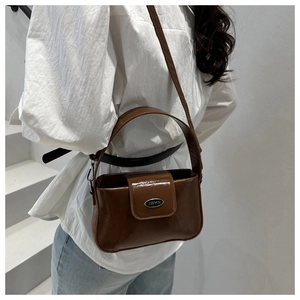 Braune Leder-Pillow-Tasche präsentiert von einem Model mit weißem Hemd und Jeans