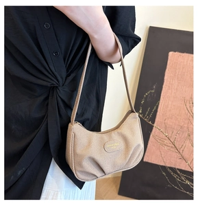 Vista dettagliata di una borsa hobo beige a pieghe con tessuto strutturato e tracolla.