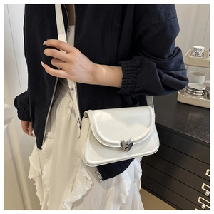 Detail showing white shoulder bag with silver heart-shaped lock on a model outfit