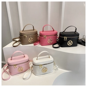 Detail showing five colors of leather vanity bags with golden M charms on white steps