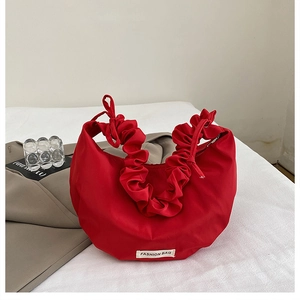 Detail of red nylon crescent bag with ruched handle and fashion tag on soft background