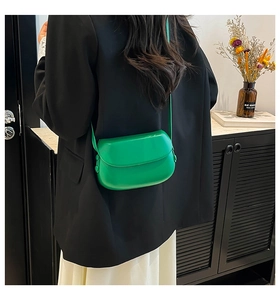 Détail d'un sac besace vert vif porté par un mannequin en costume noir élégant