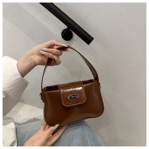 Detailaufnahme der braun glänzenden PU-Leder-Handtasche mit Metalllogo und Griff