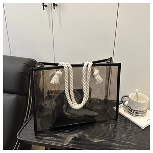 Detail of transparent PVC tote featuring thick white cotton rope handles and black leather trim