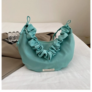 Macro detail of nylon dumpling bag featuring adjustable pleated straps and fashion tag
