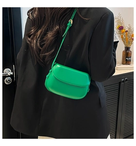 Detail of adjustable strap buckle on a green retro saddle bag over a black blazer