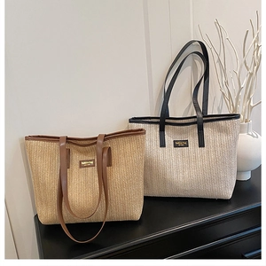 Detail view of woven straw tote bags with leather straps and golden logo plate