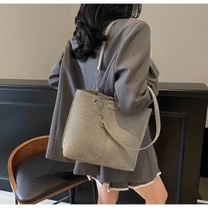 Detail of light khaki tote bag featuring metal chain woven strap and sleek texture