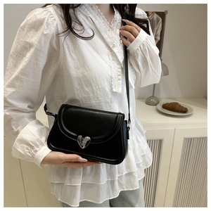 Detailed view of black leather shoulder bag featuring a silver heart-shaped magnetic buckle
