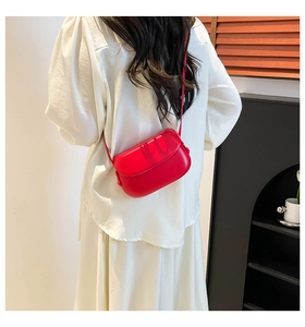 Detailed back view of a glossy red mini saddle bag worn as a crossbody on a shoulder strap