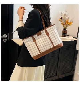 Close-up of vintage monogram tote bag with brown leather trim and metal fashion logo