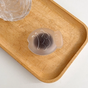 Close-up of matte pink fish-shaped phone grip on a minimalist wooden background