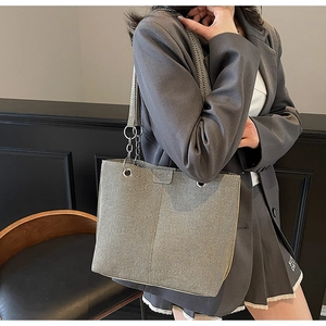 Detail of taupe twill tote bag showing chain leather strap and metal eyelets on model