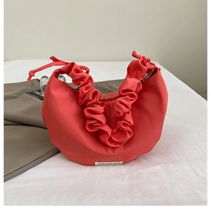 Close-up of red nylon crescent bag featuring ruched strap and FASHION BAG woven label
