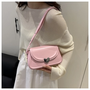 Detailed view of pink shoulder bag with heart-shaped metal buckle and leather strap