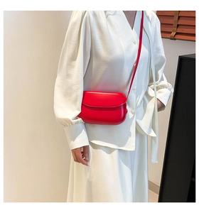 Red minimalist faux leather saddle bag worn by model with white dress for summer style