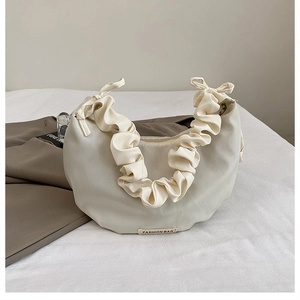 Close-up of beige nylon crescent bag with ruched handle and fashion bag label detail