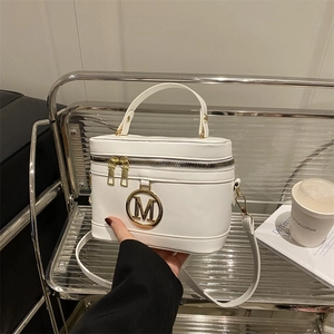 Sac seau blanc chic avec emblème M doré et poignée porté par un mannequin