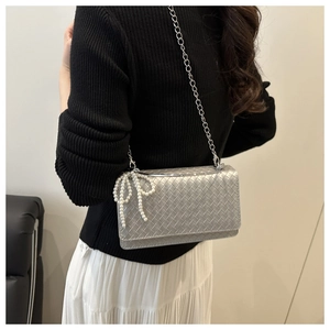 Detail of silver woven shoulder bag with delicate white pearl bow charm on the side