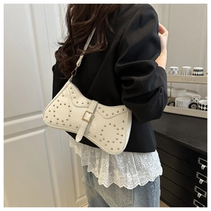 Detail of white crocodile texture crescent bag with golden studs on a female model