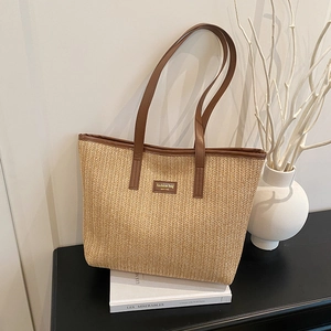 Straw tote bag with brown leather trim and V-shaped weave for summer vacation