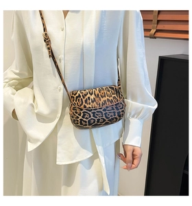 Detail of leopard print saddle bag with adjustable strap worn on a white shirt
