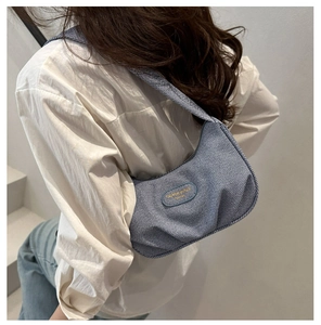 Vista dettagliata di una borsa sottobraccio in denim a righe blu indossata su camicia
