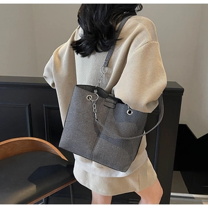 Close-up of dark grey textured tote bag featuring stylish metal chain and leather strap