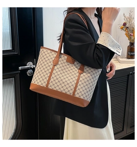 Detail of vintage tote bag featuring classic plaid pattern and brown leather trim accents