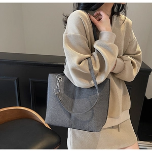 Detail view of a grey minimalist tote bag with metal chain strap and vertical stitching