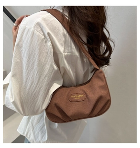 Vista dettagliata di una borsa sottobraccio marrone a pieghe indossata da modella