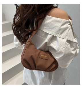 Vista dettagliata di un'elegante borsa a tracolla plissettata marrone su una modella