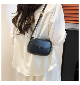 Side view of a black leather saddle bag with adjustable strap and gold hardware