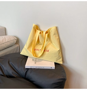 Detail of light yellow tote bag with ANYUN ICAI red print on textured canvas fabric