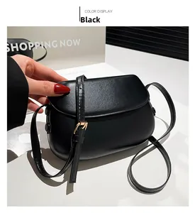Detail of a black minimalist saddle bag showing smooth leather texture and gold buckle