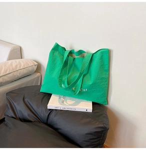 Detail of green canvas tote bag with white lettering on a black sofa chair