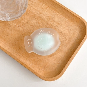 Macro shot of fish-shaped phone grip with frosted translucent texture on wooden tray