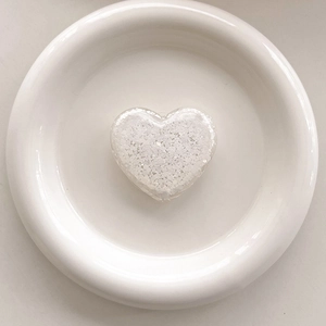 Macro shot of heart-shaped phone grip with white glitter inside on white porcelain plate