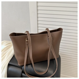 Macro view of brown tote bag featuring elegant white contrast stitching and smooth leather