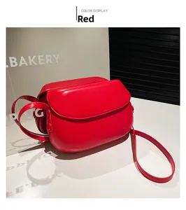 Detailed view of glossy red saddle bag with smooth leather finish and metallic side buckle