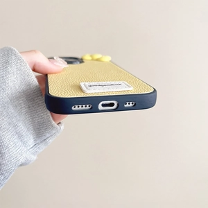 Detail of yellow leather iPhone case with black trim and white embroidered patch